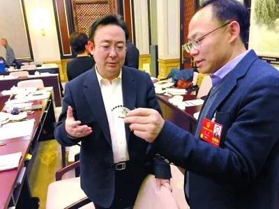 昨天,北京團小組會休息的間隙,程京代表(右)向夏林茂代表介紹基因芯片。張宇攝